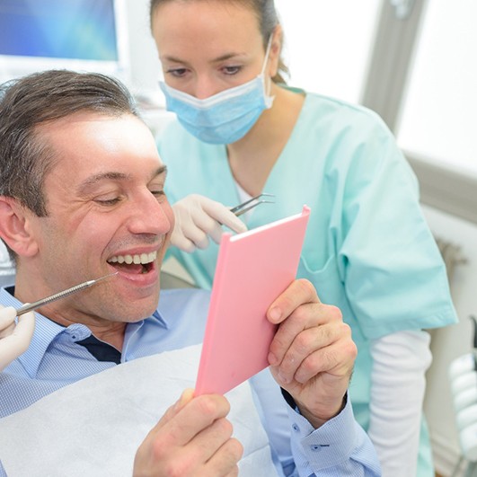 patient looking at teeth in dental mirror