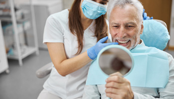 Patient looking at reflection in mirror with dentist