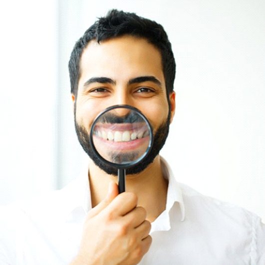 man holding a magnifying glass to his smile