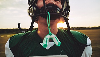 Young child wearing a football helmet with mouthguard attached