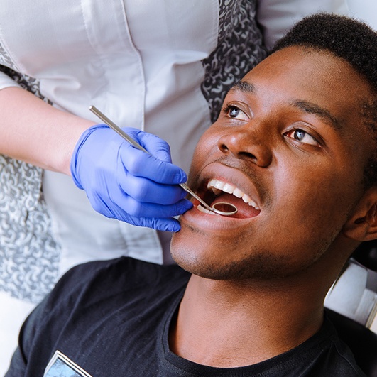 Man preventing dental emergencies in Eatontown by visiting a dentist
