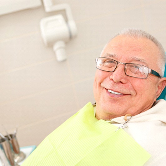 Man with implant dentures in Eatontown smiling in dental chair