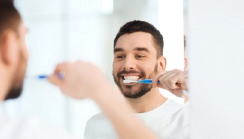 man brushing his teeth in front of a mirror