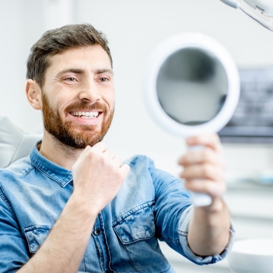 Man looking at smile after dental implant tooth replacement