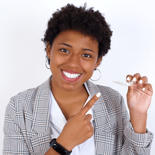 Happy young businesswoman pointing at her clear aligner