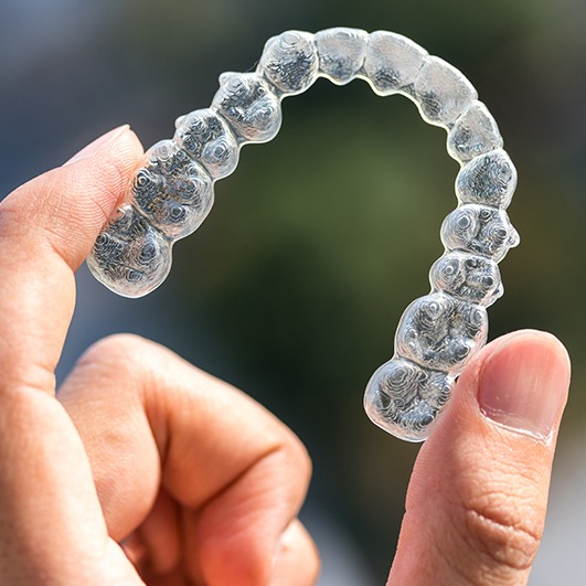 Patient holding an Invisalign tray for orthodontics treatment