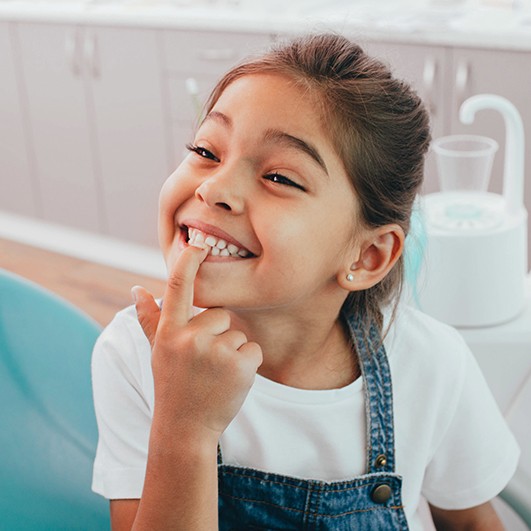 Little girl pointing to her smile after children's dentistry treatment