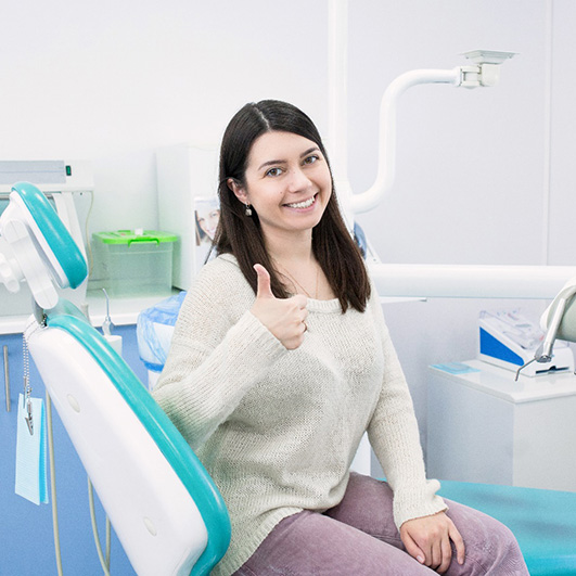 Young woman giving thumbs up after root canal therapy in Eatontown, NJ