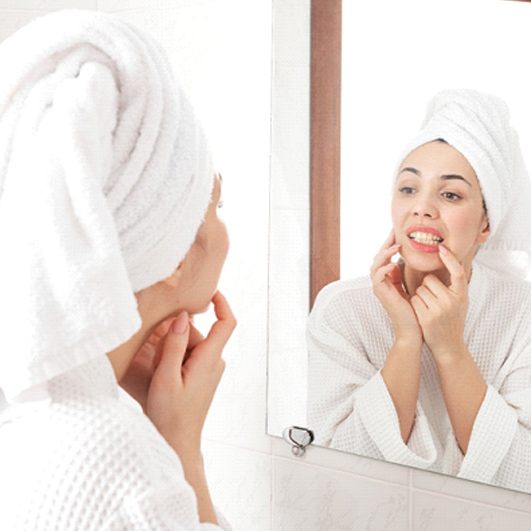 Woman looking at her teeth in bathroom mirror