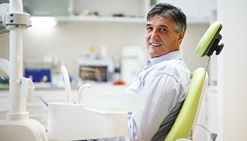 Man in collared shirt smiling while sitting in dental chair