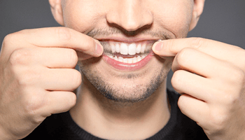a man using a teeth whitening strip