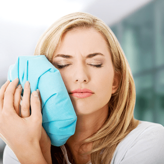 a woman using an ice pack on her jaw