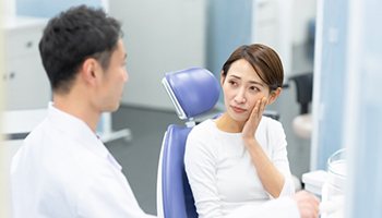 a patient holding her cheek due to wisdom tooth discomfort