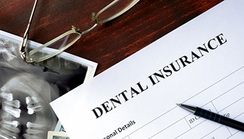 a dental insurance form next to a dental X ray 