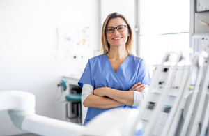 Dental assistant with glasses smiling with arms folded