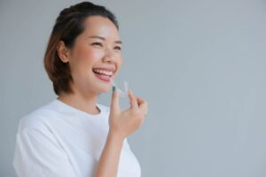Smiling woman holding a clear aligner close to her mouth