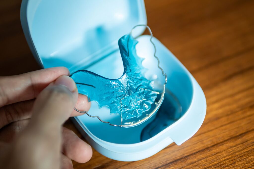Fingers placing blue retainer into carrying case