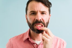 Man pulling down bottom lip to show red gums.